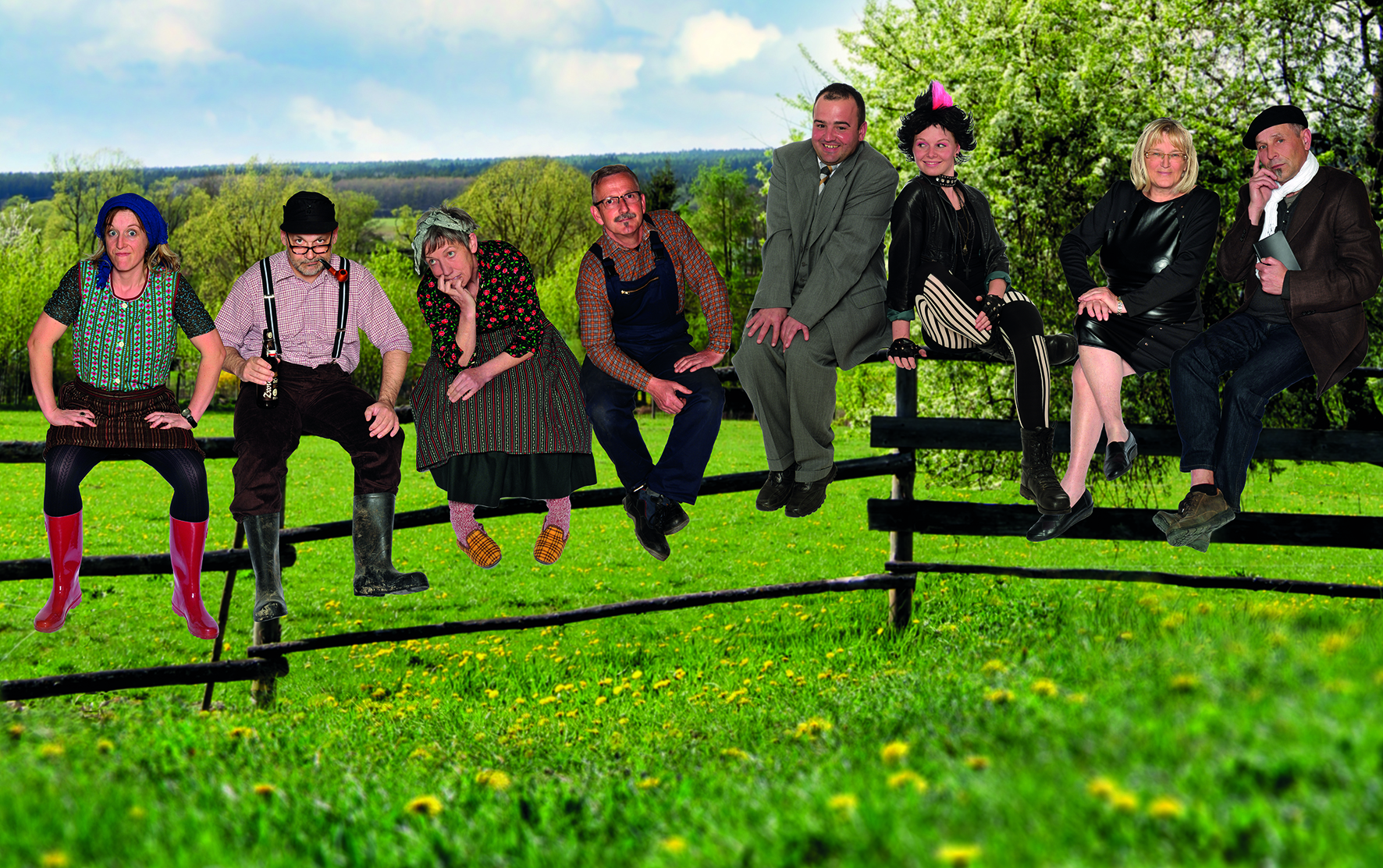 Das Bild zeigt eine Gruppe von 8 Menschen, die auf einem hölzernen Weidezaun sitzen. Die Weide ist grün, der Himmel im Hintergrund blau.
