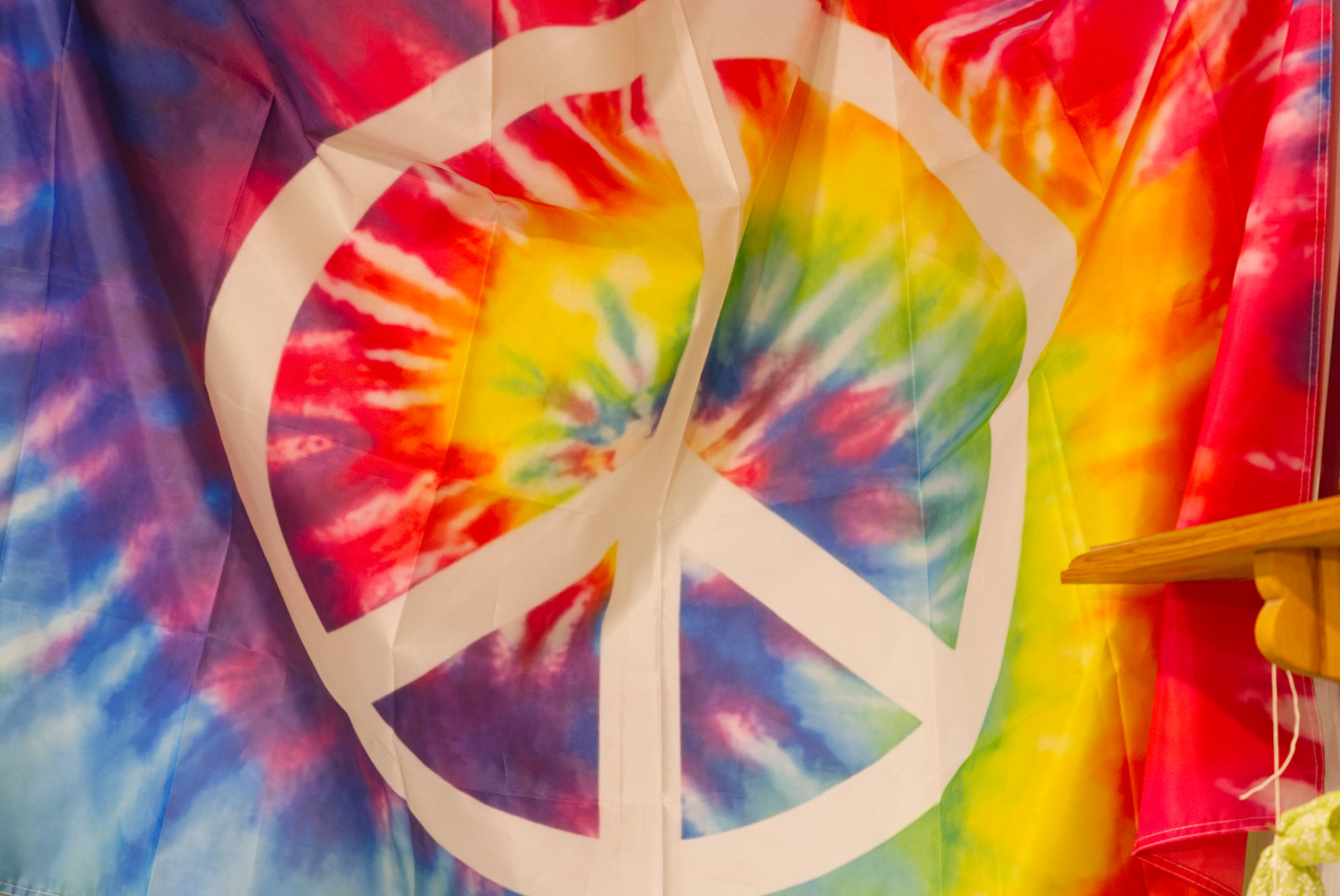 Nahaufnahme einer Flagge mit Peace-Symbol auf einem bunten Batik-Hintergrund